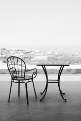 Fototapeta premium Metal chair and table a beautiful place to rest on the terrace of the house with a view of SANTORINI, GREECE.