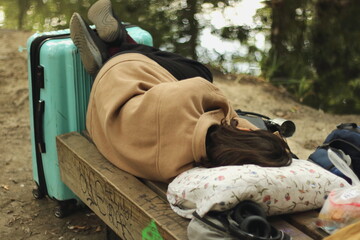Female Traveler Sleeping on a Bench with a Huge Bag Due to Delayed Departure