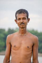 Riverside people of Bangladesh. A fisherman stands in the twilight horizon behind the river bank.