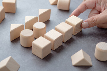 Closeup hand of man pick the wood block, categorize geometric wood toy into the row