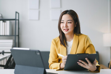 Young businesswoman is taking notes while having a video call on a tablet in her office