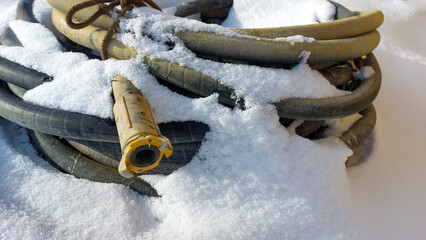Winter, on the snow lies a thick hose, coiled into rings from a sandblasting machine, a Baynet type...