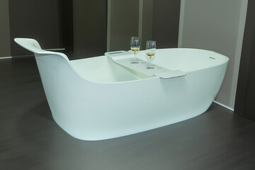 Empty bath tub in the middle of the bathroom interior with serving champagne on a tray