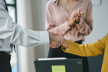 Business team celebrating a successful deal in the office, shaking hands and clapping