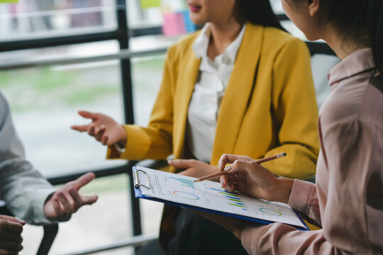 Business team having a discussion and analyzing financial data on a clipboard during a meeting