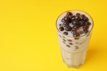 Tasty milk bubble tea in glass on yellow background, closeup. Space for text
