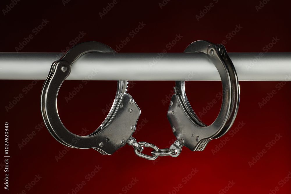 Wall mural Metal chain handcuffs on pipe against dark background, closeup