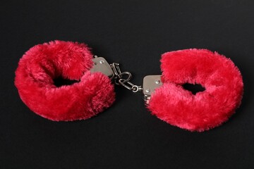 Bright fluffy handcuffs on black background. Sex toy