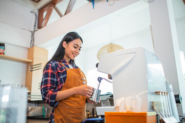 female waitress wearing apron making coffee using coffee maker at coffee shop