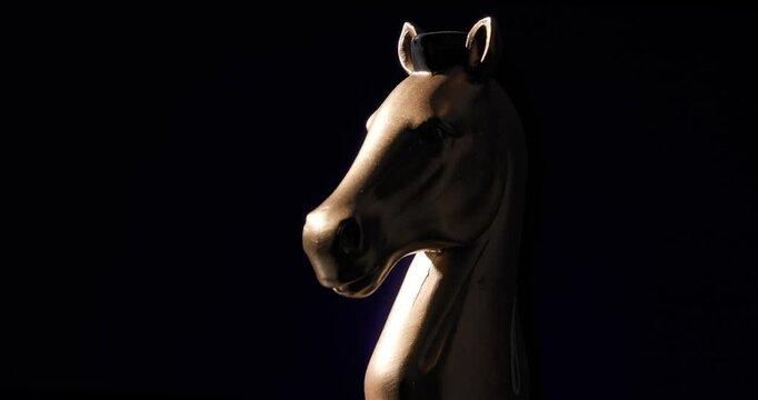 the symbol of nobility and strategy illustrated by elegant bronze statue of horse head with distinctive shape spinning in front of dark background