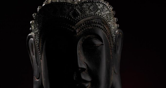 rotative Buddha head statue with elegant crown illustrating the concept of inner peace and mind meditation while spinning in front of dark background