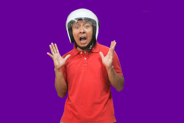 Mature Asian man wearing a motorbike helmet with a surprised face on a purple background With copy space
