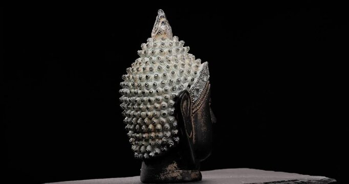 project video of rotative buddha head statue with luxury crown presenting the concept of serenity and peace of mind in front of black background