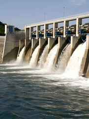 A dam releasing water into a river, showcasing hydroelectric power generation.