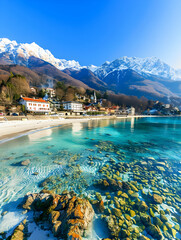 A scenic beach with clear waters, rocky formations, and mountains in the background.