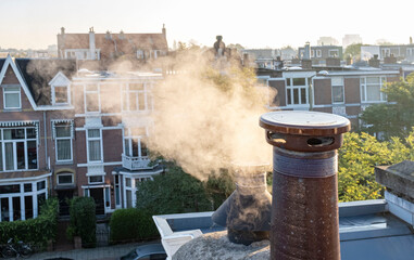 Smoke chimney pipe roof house sun autumn morning city Netherlands