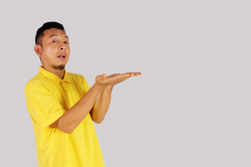 An Asian adult man opens both hands with an open mouth expression, for business and food advertising.