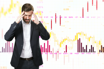 A man stressed with hands on head, stock market chart background