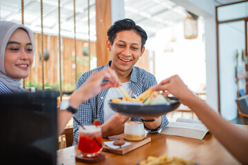 male students laugh while enjoying a meal together at a coffee shop