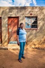 african village, portrait of single african woman with scarf in front of her house