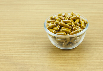 Turmeric capsule powder on wooden background