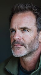 Obraz premium A contemplative middle-aged man with blue eyes, exuding calm in a natural setting