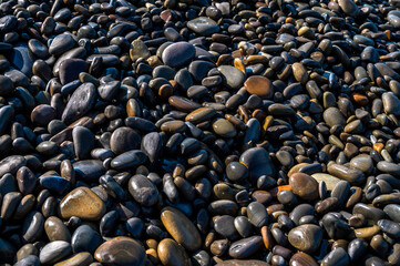 Wet sea pebbles close-up. Rocky beach on the sea, ocean, river, lake, pond. Natural background for design.