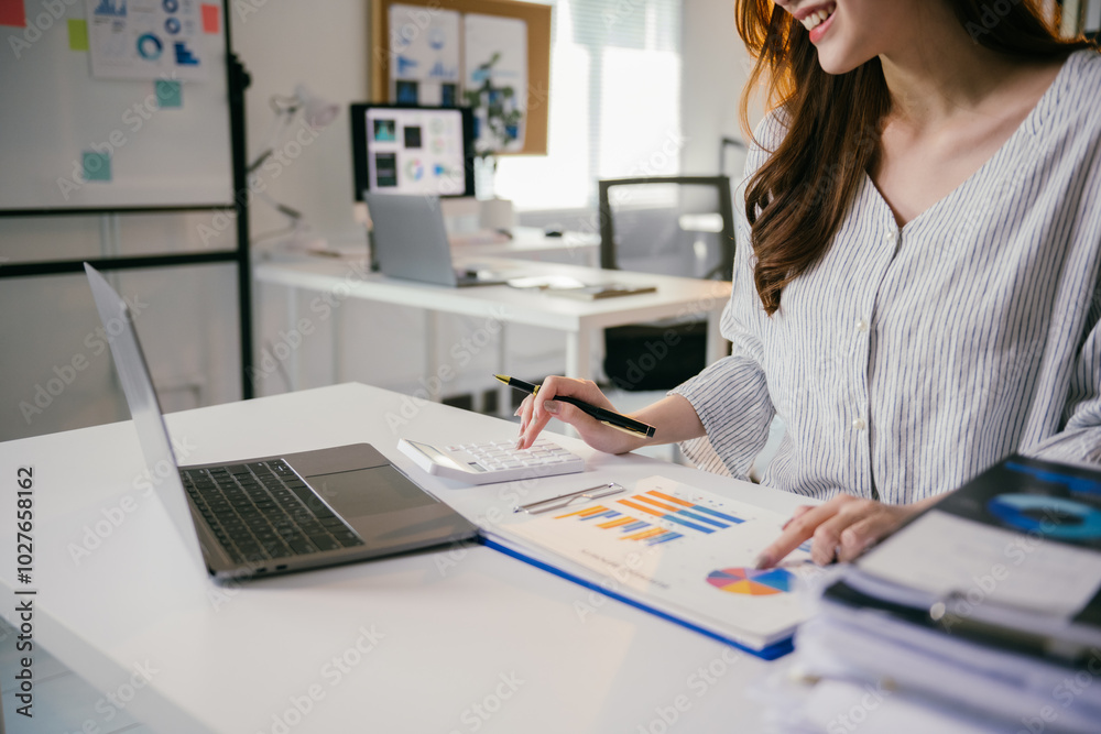 Aufkleber businesswoman is analyzing financial data using a calculator and working on a laptop, with charts an