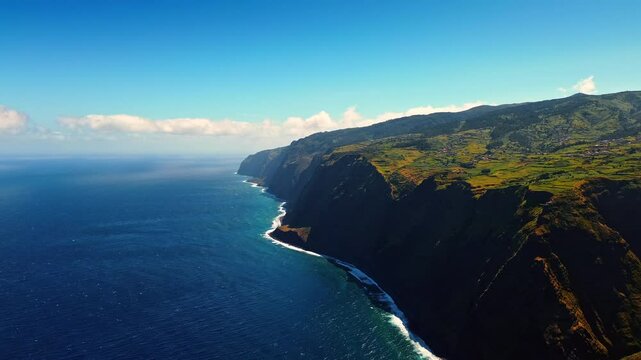 Dangerous inaccessible steep rocks descending into the ocean. Sunny view of the coast at Madeira Islands, Portugal. Aerial view.