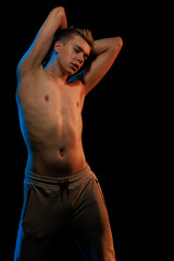 Naklejka premium Young man posing in the dark with red and blue light in the studio