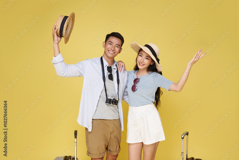 Wall mural happy fun asian couple traveling vacation portrait with suitcase ready for travel isolated on yellow