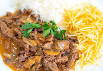 Traditional filet mignon stroganoff with mushrooms, French fries and rice