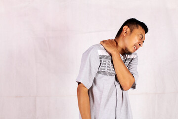 Shoulder pain concept. asian man feeling pain holds shoulder with hand with painful expression
