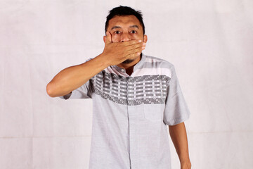 Mature Asian man covers his entire mouth with his hand
