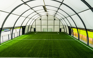 interior of a covered football pitch with grass and a football goal in the middle, light and space, grass roof, football stadium,