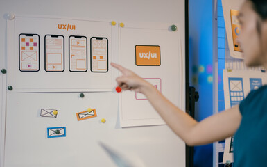 Ux ui designer pointing at a whiteboard with website wireframes and explaining the design process...