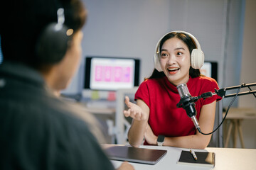 Female podcaster and her male co-host record a podcast in their cozy home studio, deep in conversation surrounded by microphones and headphones, showcasing the joy of content creation