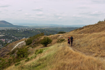 Young couple walking up hill of a high mountain, beautiful view surrounds them