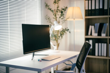 Modern office workspace is bathed in warm light, featuring a desktop computer displaying a blank screen, perfect for showcasing productivity or design concepts