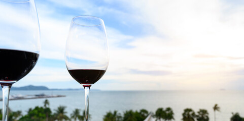 A glass of red wine on black table against the backdrop of the summer beach. Glasses of red wine on vacation. Wine tasting and relaxation at the resort. Copy space.