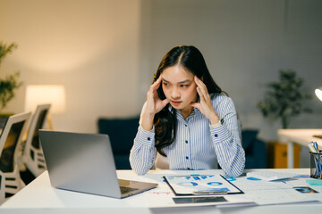 Stressed businesswoman working late at night on laptop, feeling exhausted and overwhelmed