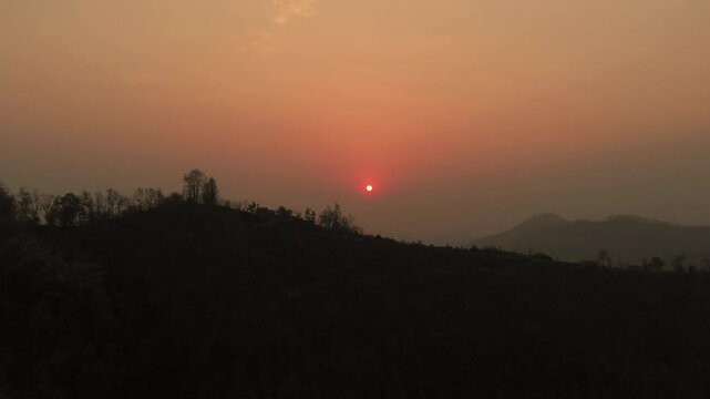 Beautiful Sunset, silhouetted against the warm hues of a setting sun in the hilly region and mountains in the background, Nepal