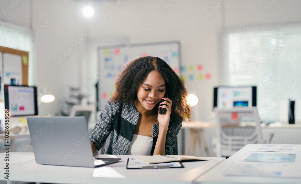 Aufkleber Young manager is working in a luminous open space and handling business on the phone, she is smiling and seems focused