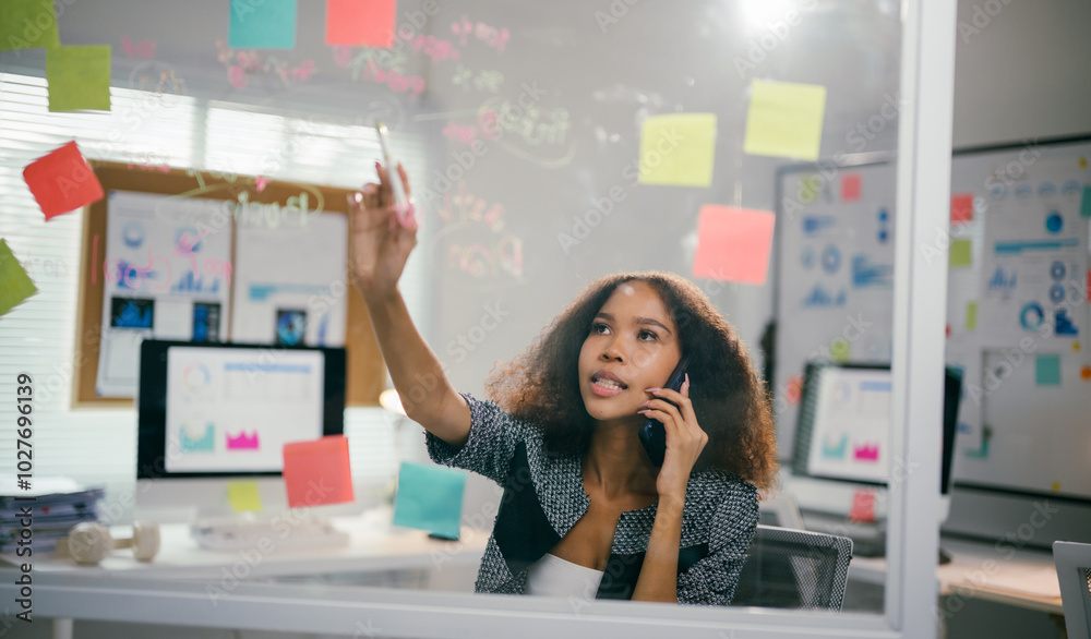Poster young manager multitasks in a modern office, brainstorming project ideas while writing on a glass wa