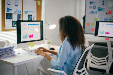 Young african american businesswoman is working on a report, looking at data on her computer screen in a bright modern office