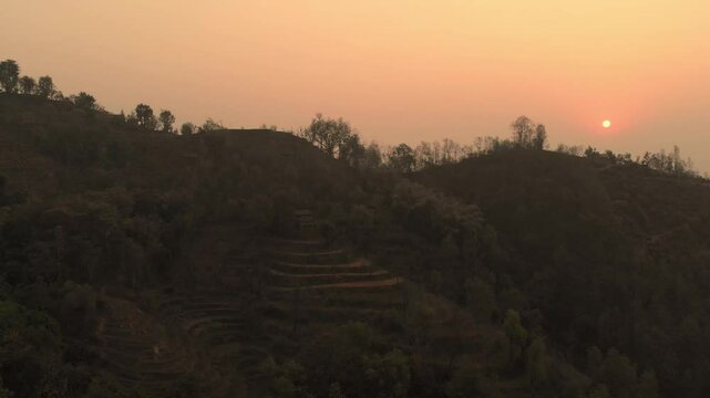 Beautiful Sunset, silhouetted against the warm hues of a setting sun in the hilly region and mountains in the background, Nepal