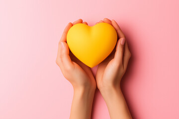 Female hands holding a yellow heart-shaped object on a pastel background