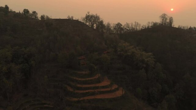 Beautiful Sunset, silhouetted against the warm hues of a setting sun in the hilly region and mountains in the background, Nepal