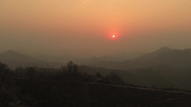 Beautiful Sunset, silhouetted against the warm hues of a setting sun in the hilly region and mountains in the background, Nepal