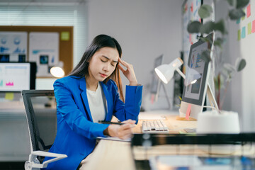 Stressed businesswoman with headache from overwork at laptop in office, showing burnout effects in...